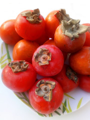 heap of ripe persimmon at dish. close up