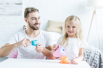 Obraz premium happy father and daughter playing together and pretending to have tea party