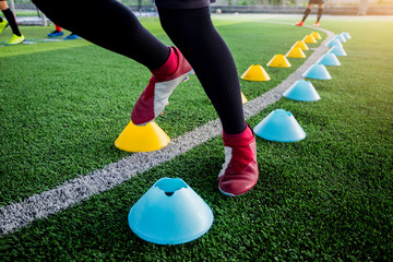 Soccer player Jogging and jump between cone markers on green artificial turf for soccer training.