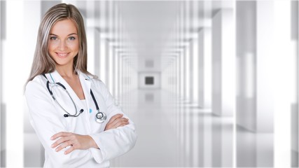 Attractive young female doctor with blurred hospital interior on