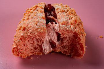 front view of half eaten strawberry flavor bread on pink