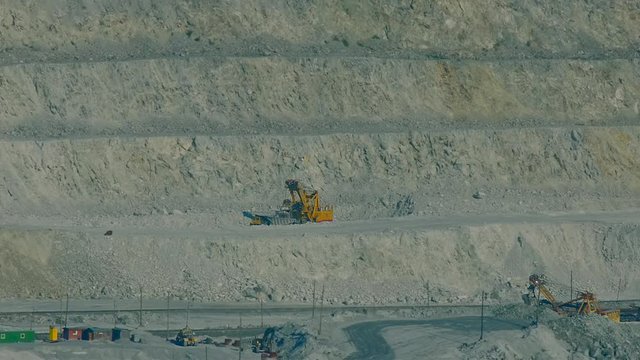 excavators operate on  asbestos open cast quarry ledges