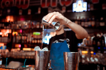 Barman pouring a cocktail into a glass
