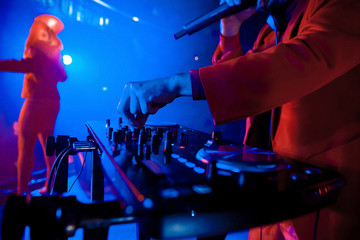 Dj mixes the track in the nightclub at party. In the background laser light show