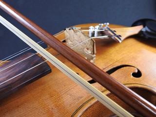 Close-up of a violin, a wooden string instrument, and a bow. Focus highlights the bow.