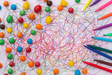 different colors felt tip pen scribble on white paper and scattered candies, abstract, creative concept, children drawing