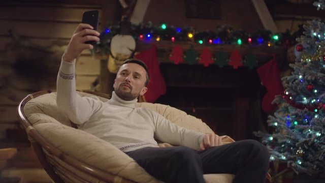 Adult man takes selfie on smartphone in Xmas night