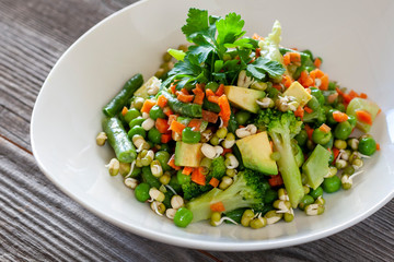 Vegetarian food: Beautiful delicious salad with avocado, broccoli, carrot, green peas, green beans with sprouted seeds.