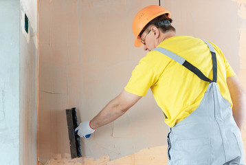 The construction worker putty a wall.