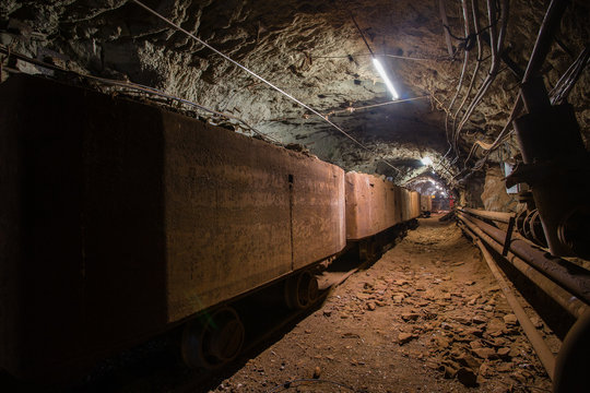 Underground gold iron ore mine shaft tunnel gallery passage with light and wagons