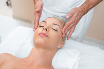 Fototapeta na wymiar Male masseur doing massage to woman in spa room