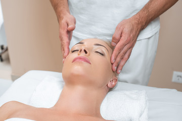 Fototapeta na wymiar Male masseur doing face massage to woman in spa salon