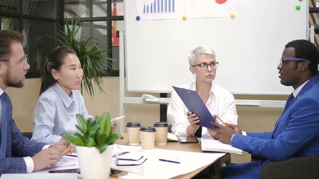 Multi-ethnic team working together in office board room. Sales executive, boss, financial analytic and lawyer discussing business plan.