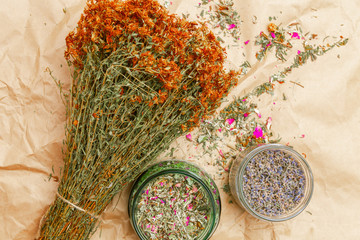 Fototapeta na wymiar bunch of dried flowers, Hypericum, phytotherapy herbs tutsan and glass jars with herbs lavender and phytotherapy tea mixo n wrinkled paper