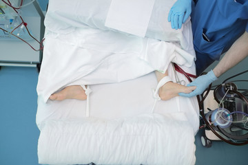 Medical person working with patient attached to bed and connected to medical equipment
