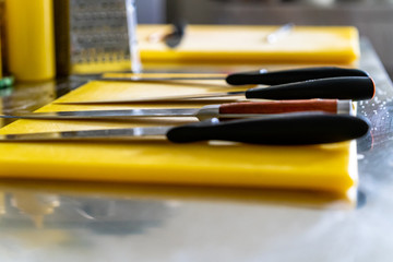 Sharp Knives with Black Handles Laying on Table with Yellow Board