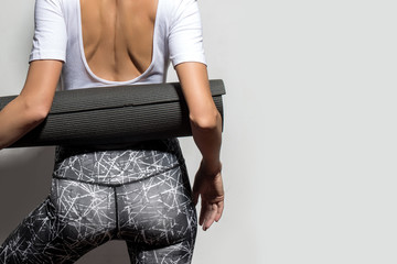 Athletic woman with yoga mat over grey background