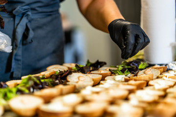 Female Chef Putting Ingredients of Burgers on a Sliced Bread Spread on a Table