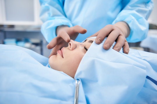 Doctor making rhinoplasty to lady. Surgeon palpating female patient nose