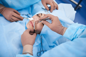 Top view photo of medical operation. Surgeon holding forceps while second doctor using tool with cotton wool - obrazy, fototapety, plakaty