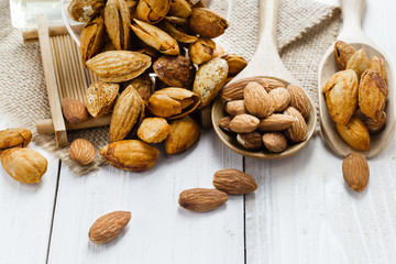 Almonds in a black bowl against dark rustic wooden background