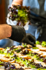 Male and Female Chef Putting Ingredients of Burgers on a Sliced Bread Spread on a Table