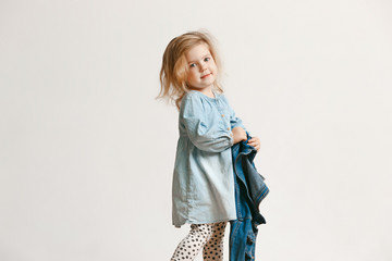 Full length portrait of cute little kid girl in stylish jeans clothes looking at camera and...