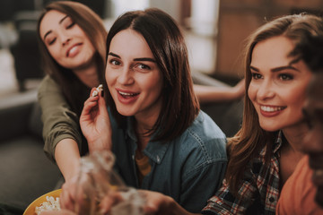 Portrait of beautiful young ladies eating popcorn and smiling