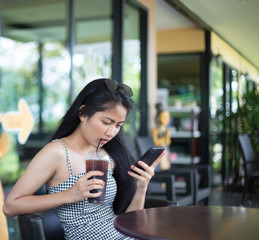 asian woman enjoy with her coffee and holding the cellphone