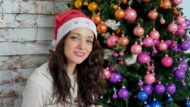 Young woman in santa hat near christmas tree