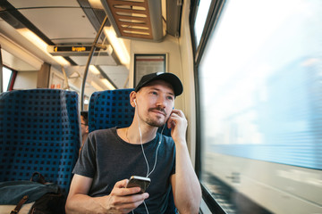 A young man listens to a music or podcast while traveling in a train.