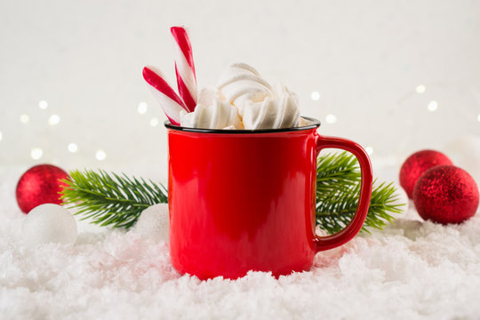 Cozy winter composition with a red cup of hot chocolate with marshmallows  on a light festive background.