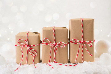 Packing Christmas gifts.  Three Christmas gift boxes wrapped in kraft paper tied with red and white...