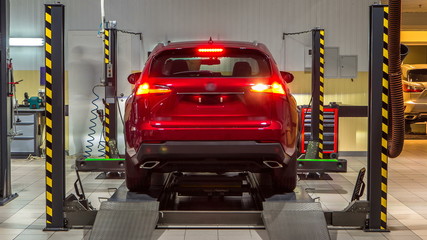 Car on stand with sensors on wheels for wheels alignment camber check in workshop of Service...