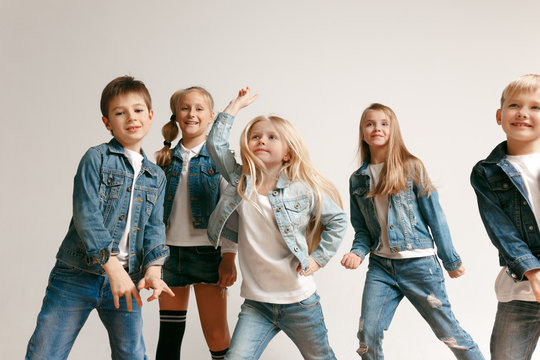 The portrait of cute little kids boy and girls in stylish jeans clothes looking at camera against white studio wall. Kids fashion and happy emotions concept