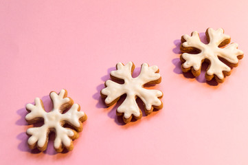 Christmas gingerbread on a pink background. Gingerbread snowflake covered with white icing.