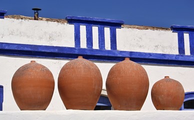 Traditionelle Tongefaesse vor einer blau weissen Mauer