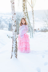 Fototapeta na wymiar A beautiful girl walks on a frozen forest covered with snow.