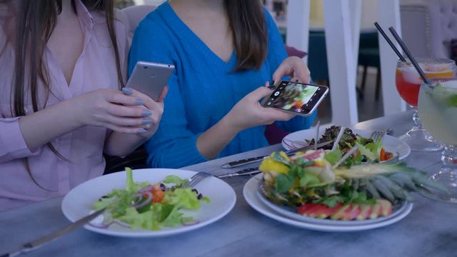 blogging, hands of female friends take pictures of beautiful useful food on mobile phone during breakfast during diet for weight loss in cafe close-up