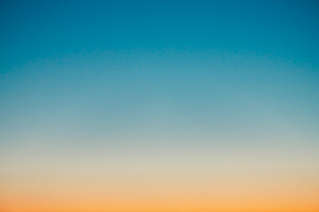 Predawn clear sky with orange horizon and blue atmosphere. Smooth orange blue gradient of dawn sky. Background of beginning of day. Heaven at early morning with copy space. Sunset, sunrise backdrop. - obrazy, fototapety, plakaty
