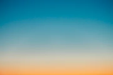 Foto auf Acrylglas Klarer Himmel vor der Morgendämmerung mit orangefarbenem Horizont und blauer Atmosphäre. Glatter orange-blauer Farbverlauf des Morgenhimmels. Hintergrund des Tagesanfangs. Himmel am frühen Morgen mit Kopienraum. Sonnenuntergang, Sonnenaufgang Hintergrund. © Daniil