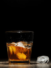 Whiskey splash in glass on a wooden table.