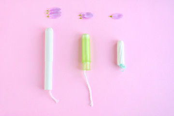 Kiev, Ukraine - 11.29.2018. Tampons with selective focus on blurred pink background with pink flower petals. Woman hygiene for period days, menstrual mothly cycle. Protective care for woman health.
