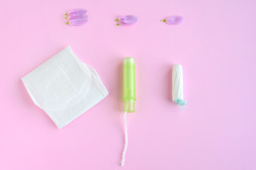 Kiev, Ukraine - 11.29.2018. Tampons with selective focus and petals on pink background. Woman hygiene for period days. Ginecology pads for menstrual mothly cycle. Protective care for woman health.