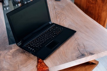  Wooden table in solid oak with epoxy resin in the office, a laptop.