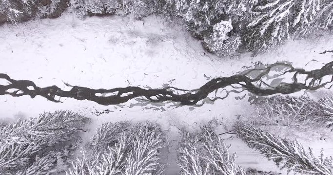 Aerial shooting. Very beautiful winter landscape. Snow covered mountains. Winter mountains. the camera rises up from the river to the treetops. Snow falls