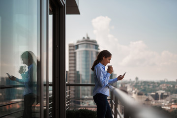 Take a pause. Portrait of smiling businesswoman reading massages on smartphone while having coffee...