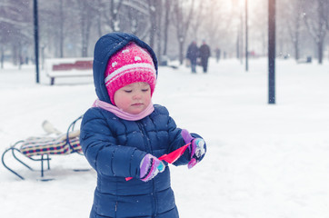 Fototapeta na wymiar Little girl walks on the street in the winter day