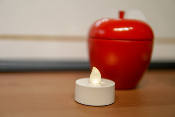 Red apple shaped container with white candle ornament