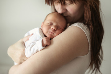 Ordinary mother hugs and kisses newborn baby - obrazy, fototapety, plakaty